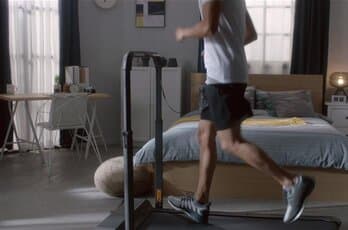 Man running on a treadmill in his home with furniture in background