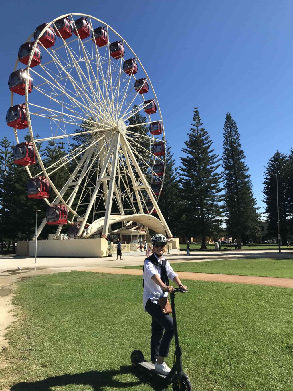 a rider posing with her ninebot g30p max kickscooter with a giant wheel behind