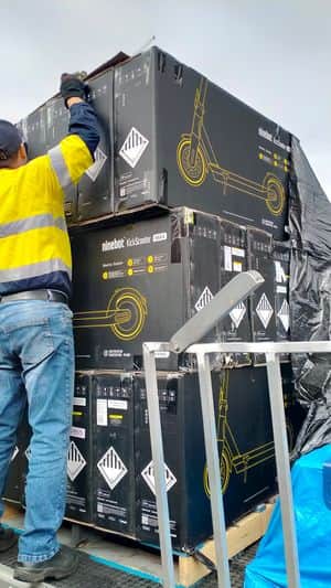 worker wearing reflective clothing is unloading a pallet full of factory refurbished segway ninebot max g30